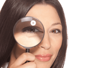 A lady holding up a magnifying glass to one eye.