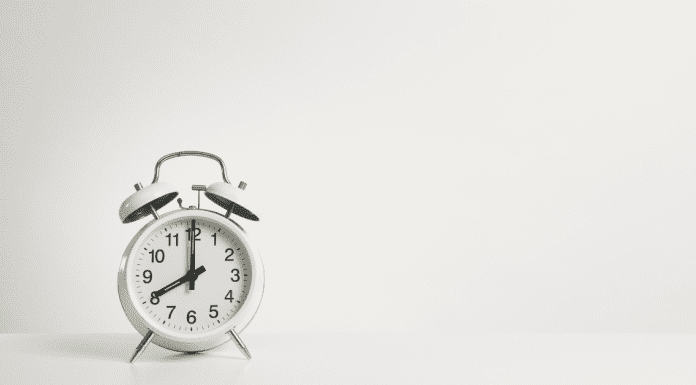 An alarm clock, set to 8am, against a white background