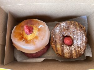 two donuts sit side by side- The creme brûlée donut and Nutella cronut from Local Donut- both have a raspberry in the middle
